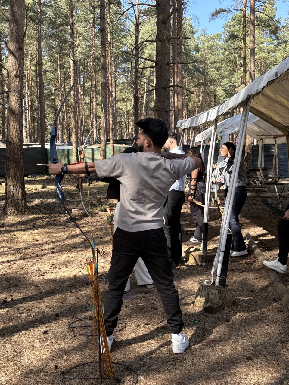 Adult archer drawing back a bow on the woodland range