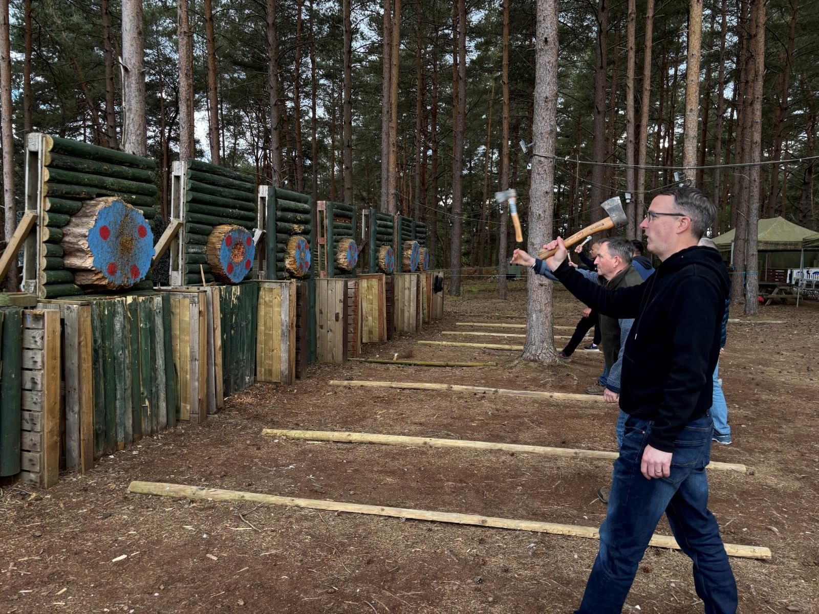 Thrower releasing a hatchet towards timber targets at the woodland axe throwing lanes