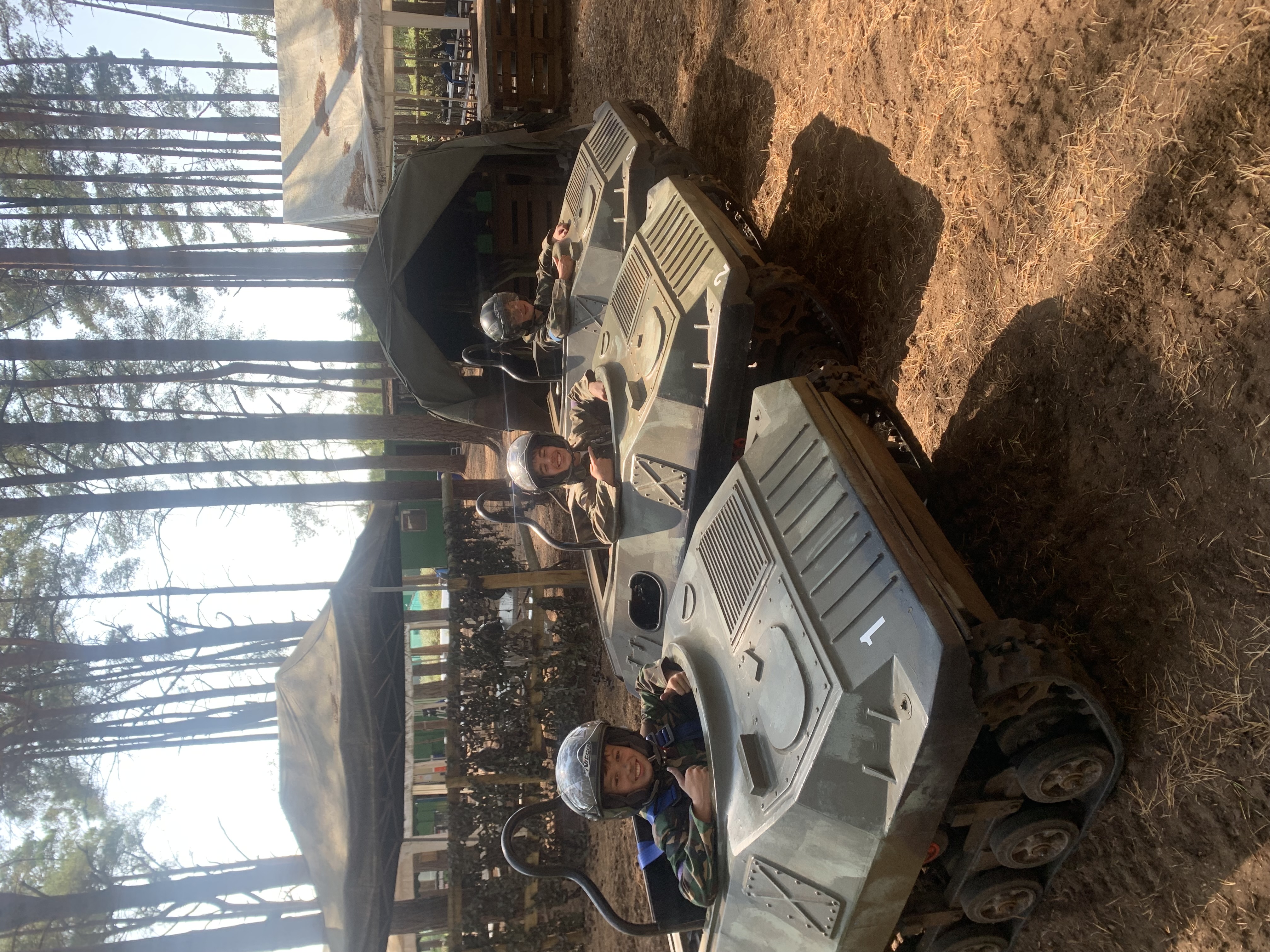 Children driving mini tanks on the woodland course